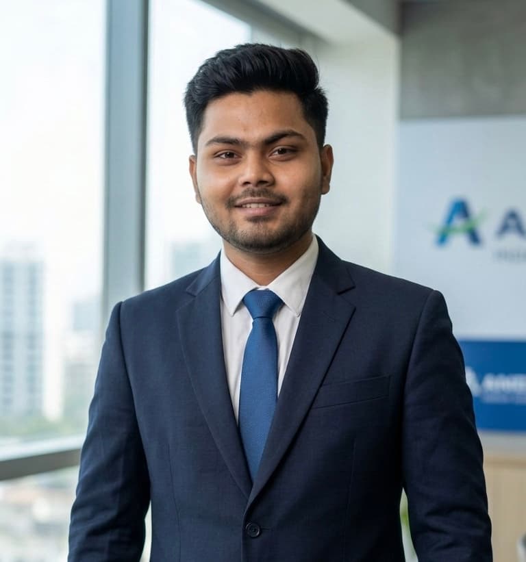 Smiling young man in a navy suit and blue tie posing in a bright office.